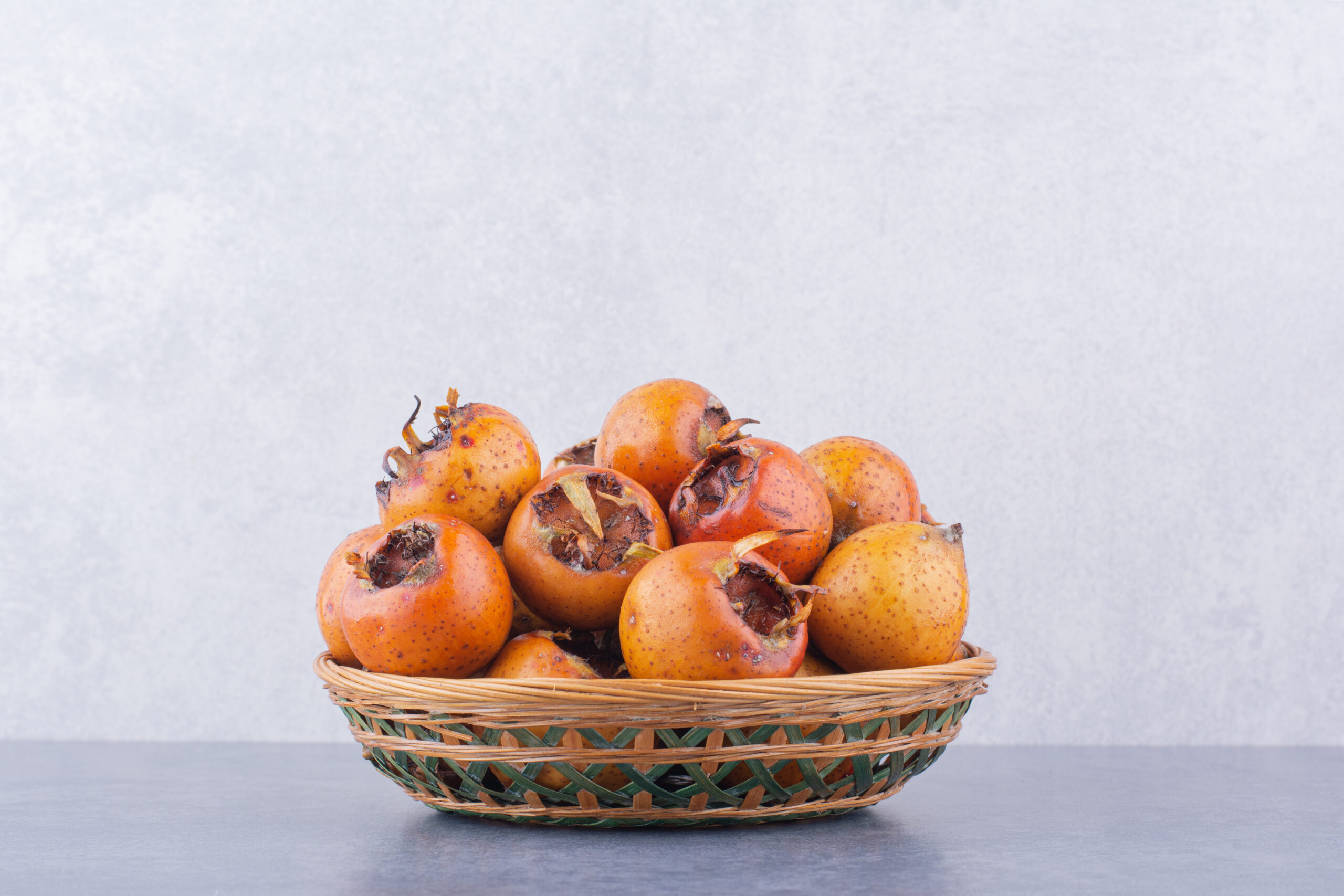 Brown medlars in a wooden platter on blue background. High quality photo