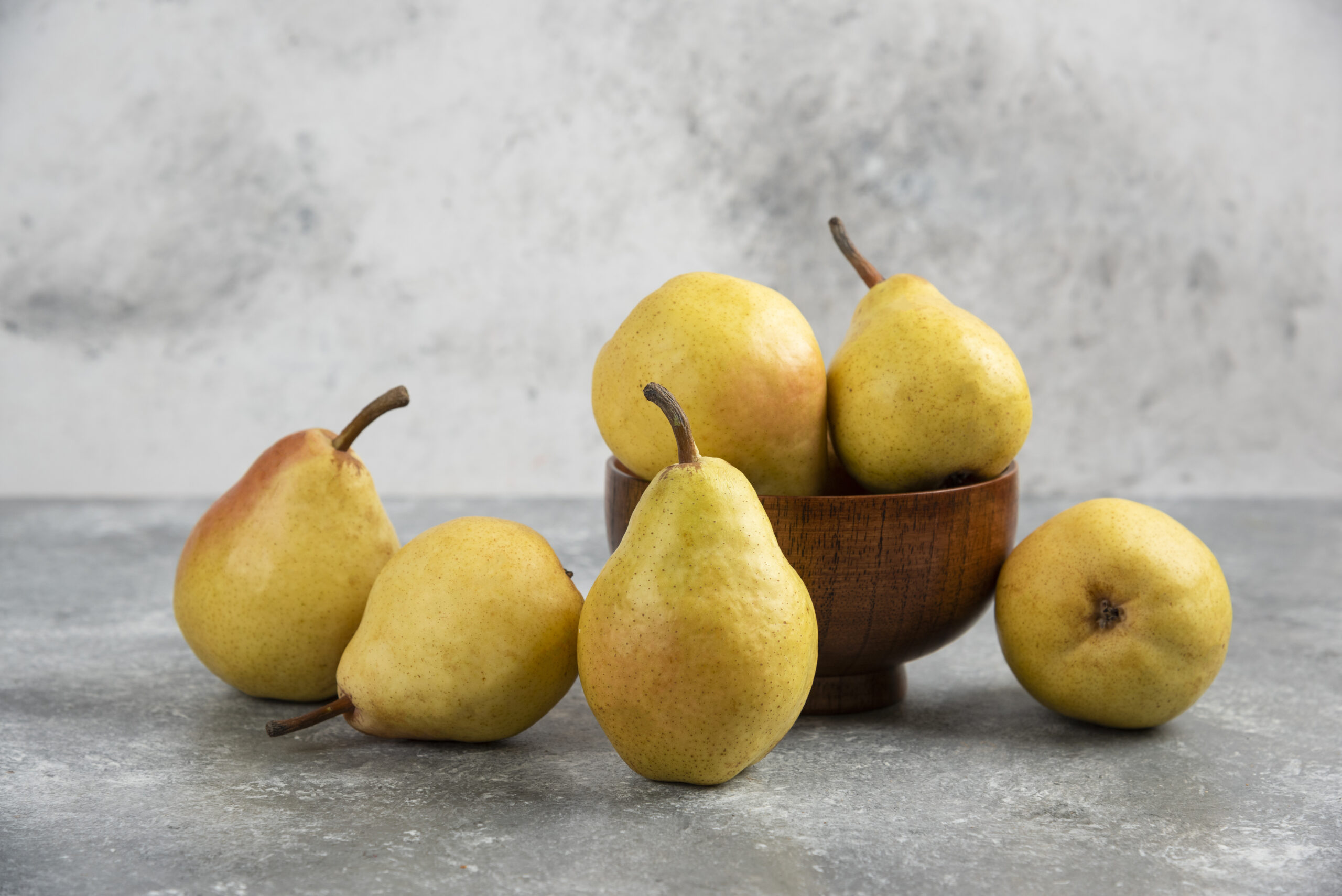 Bunch of fresh bio pears in wooden bowl on marble surface. High quality photo