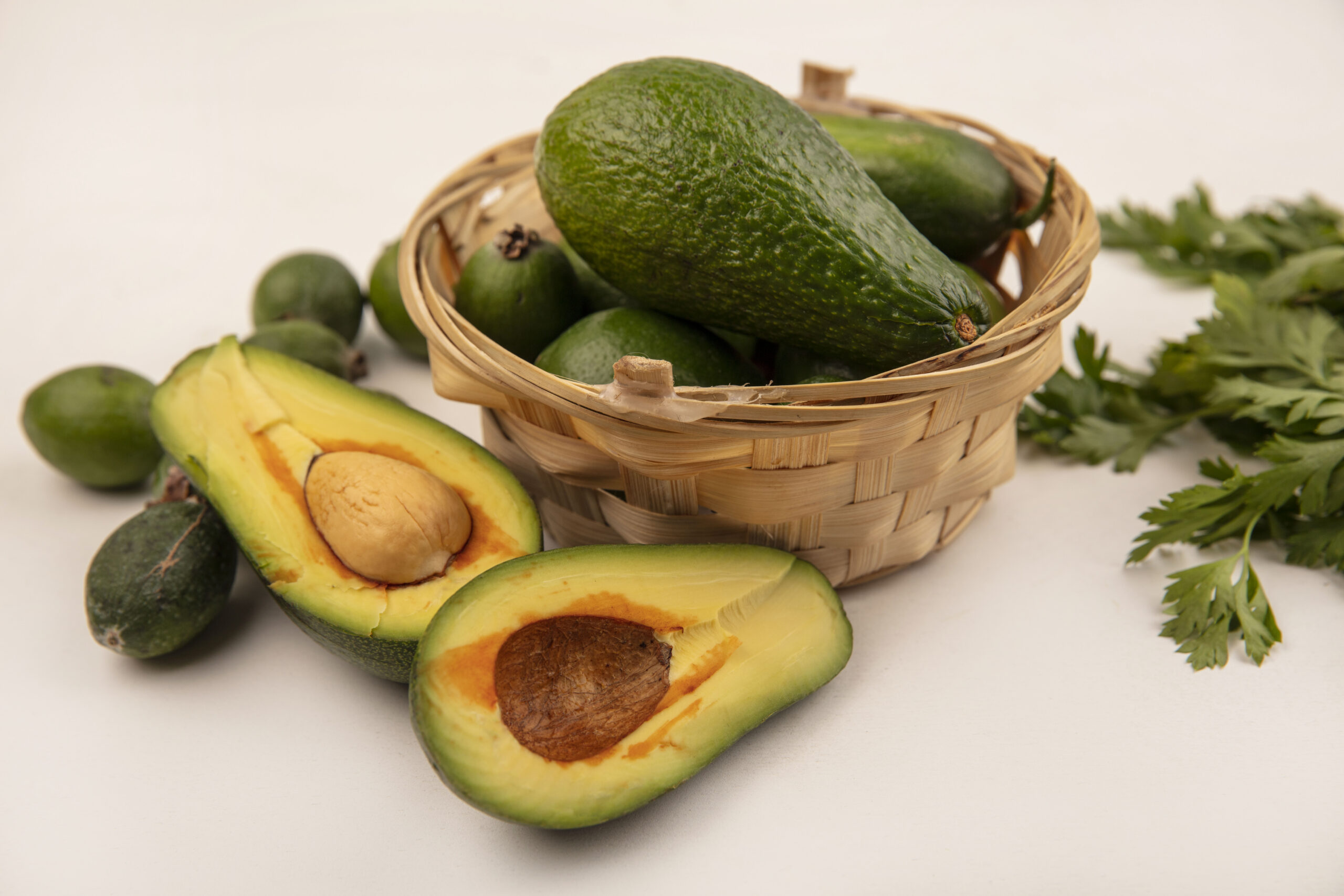 top view of bright fresh avocados on a bucket with feijoas with half avocados isolated on a white background