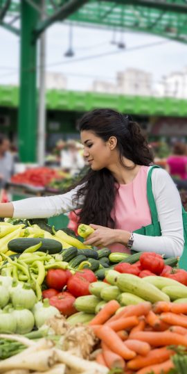 Pretty young woman buying vegetables on the market